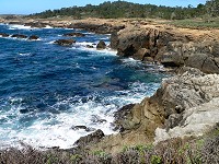 Surf is biting into a rocky edge of Point Lobos