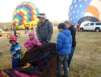 Kids helping with a balloon envelope.