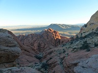 Vyhlídka z hřebínku nad jezírkem - v popředí červené skály Red Rock Canyon, vzadu Las Vegas.