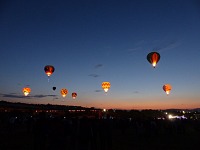 Balloons shine against the still dark skies.