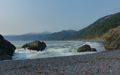 From Black Sand Beach, one can see the smoky ceiling over distant hills.