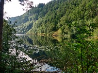Kossdalsvatnet: surrounding rocky slopes reflect in the lake's surface.